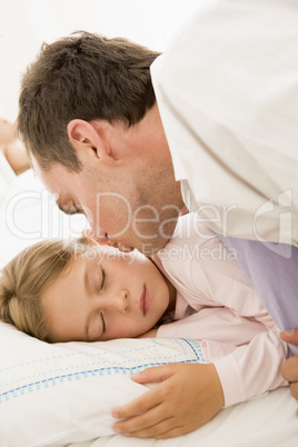 Man waking young girl in bed with kiss