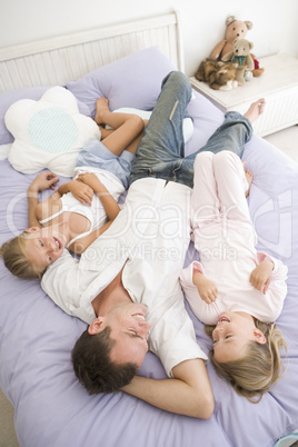 Man lying in bed with two young girls smiling