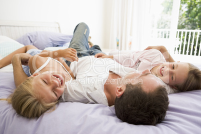 Man lying in bed with two young girls smiling