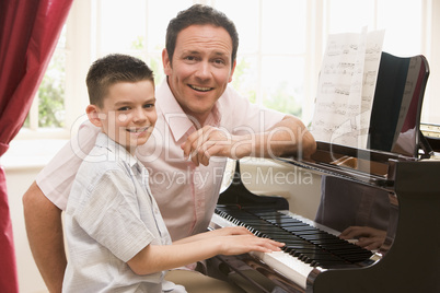 Man and young boy playing piano and smiling