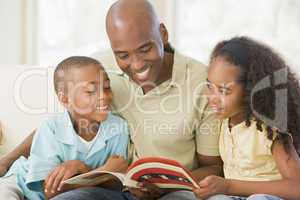Man and two children sitting in living room reading book and smi