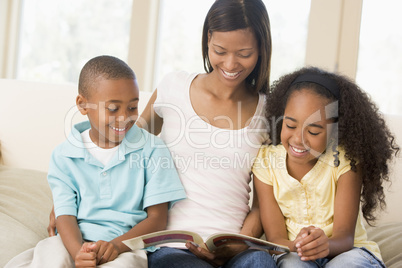 Woman and two children sitting in living room reading book and s