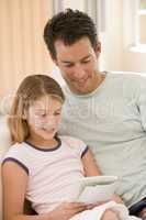 Man and young girl in living room reading book and smiling