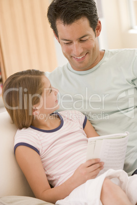 Man and young girl in living room reading book and smiling