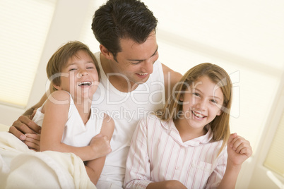 Man with two young children sitting in bed smiling