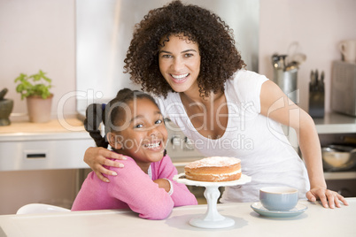 Woman and young girl in kitchen with cake and coffee smiling