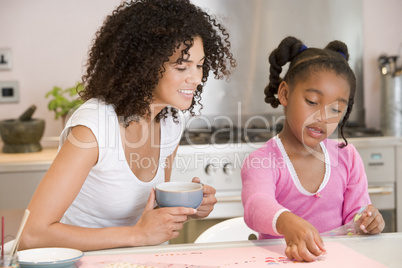 Woman and young girl in kitchen with art project smiling