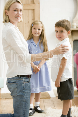 Woman in front hallway with two young children smiling