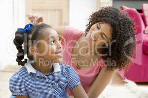 Woman in front hallway fixing young girl's hair and smiling