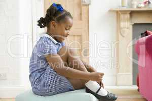 Young girl in front hallway fixing shoe and smiling