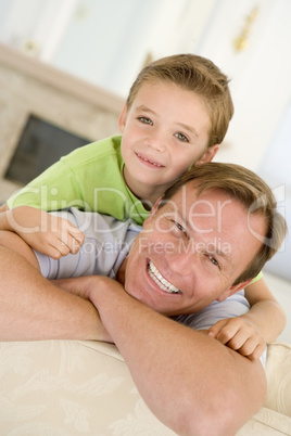 Man and young boy sitting in living room smiling