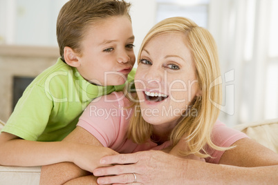 Young boy kissing smiling woman in living room