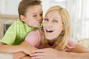 Young boy kissing smiling woman in living room