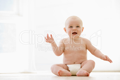 Baby sitting indoors smiling