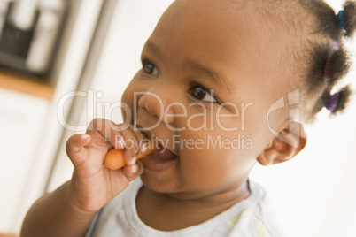 Young girl eating carrot indoors