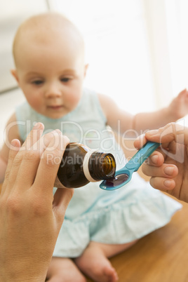 Mother giving baby medicine indoors