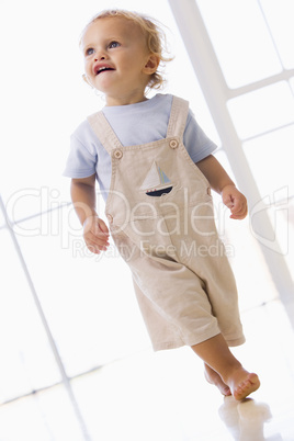Young boy walking indoors smiling