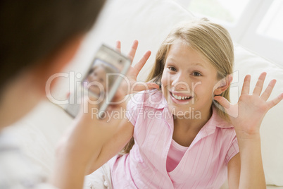 Young boy taking picture of smiling young girl with camera phone