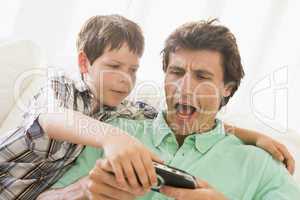 Young boy taking handheld game from unhappy man