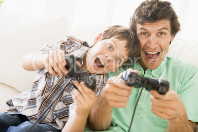 Man and young boy with video game controllers smiling