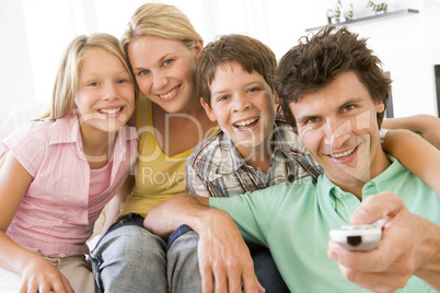 Family in living room with remote control smiling