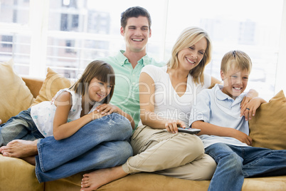 Family sitting in living room with remote control smiling