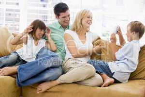 Family sitting in living room with digital camera smiling