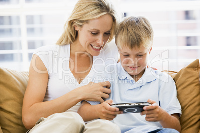 Woman and young boy in living room with handheld video game smil