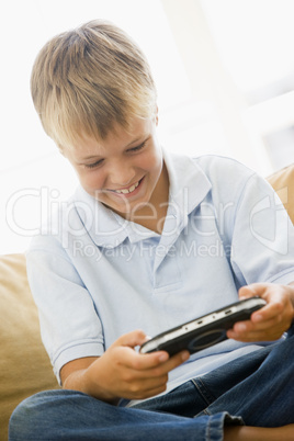 Young boy in living room with handheld video game smiling