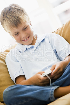 Young boy in living room with MP3 player smiling