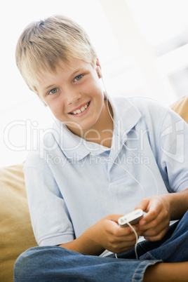 Young boy in living room with MP3 player smiling