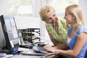 Woman and girl in home office with computer smiling