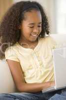Young girl in living room using laptop and smiling