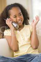 Young girl in living room using telephone and smiling