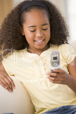 Young girl in living room using cellular phone and smiling