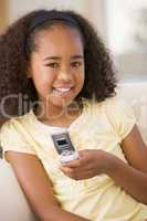 Young girl in living room using cellular phone and smiling