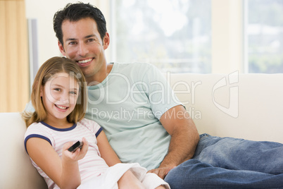 Man and young girl in living room with remote control smiling