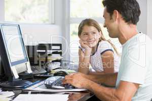 Man and young girl in home office with computer smiling