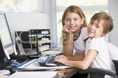 Young boy and young girl in home office with computer smiling