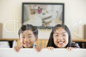 Two young children in living room with flat screen television sm