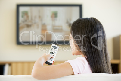 Young girl in living room with flat screen television and remote