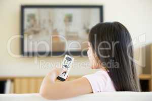 Young girl in living room with flat screen television and remote