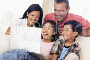 Family in living room with laptop smiling