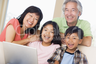 Couple with two young children in living room with laptop smilin
