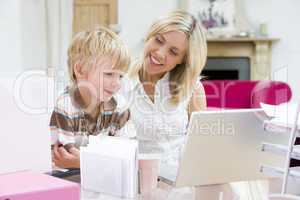 Woman and young boy in home office with laptop smiling