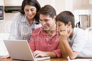 Family in kitchen with laptop smiling