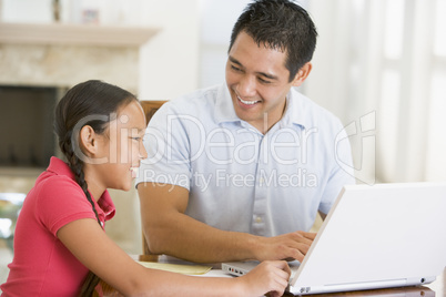 Man and young girl with laptop in dining room smiling