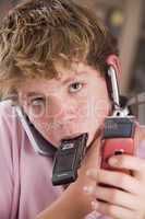 Young boy in bedroom holding many cellular phones