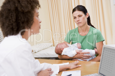 Doctor with laptop and woman in doctor's office holding baby