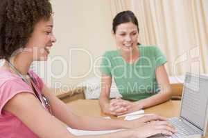 Doctor with laptop and woman in doctor's office smiling